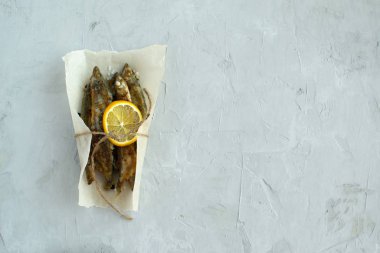 Gri bir arka planda limonlu kızarmış kapelin.