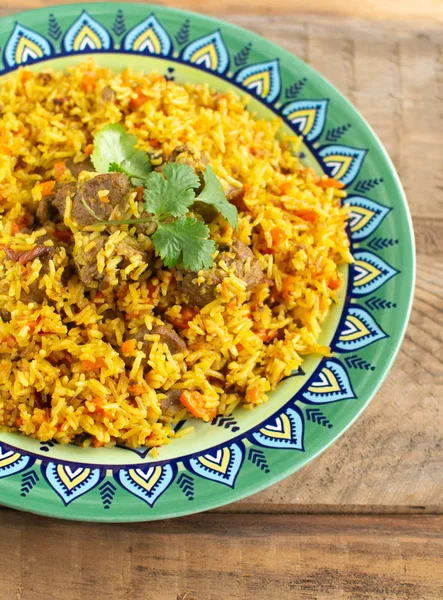 Doğu mutfağı tabağı, tavada kuzu pilavı, ahşap arka planda..