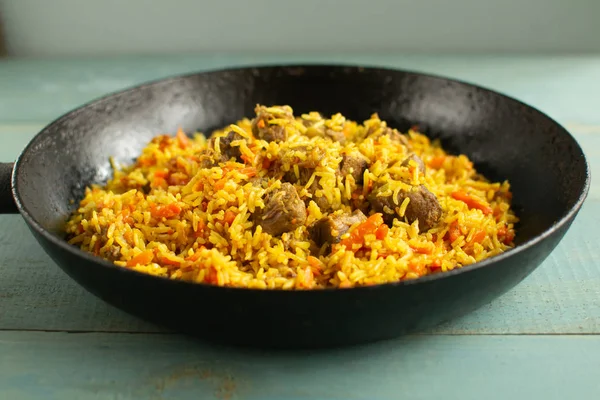 Doğu mutfağı tabağı, tavada kuzu pilavı, ahşap arka planda..