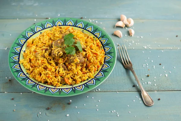 Doğu mutfağı tabağı, tavada kuzu pilavı, ahşap arka planda..