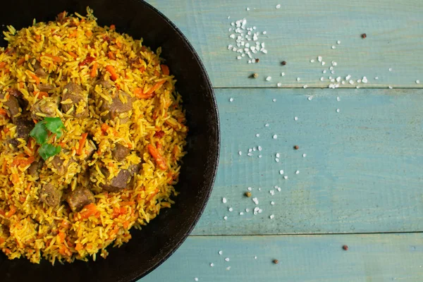 Doğu mutfağı tabağı, tavada kuzu pilavı, ahşap arka planda..