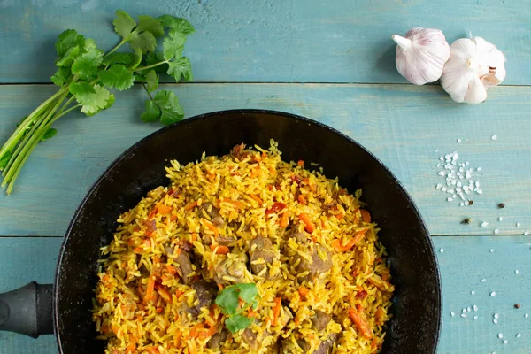 Doğu mutfağı tabağı, tavada kuzu pilavı, ahşap arka planda..