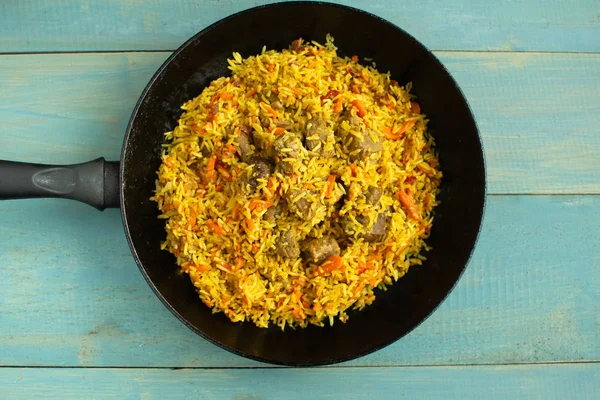 Doğu mutfağı tabağı, tavada kuzu pilavı, ahşap arka planda..