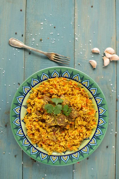 Doğu mutfağı tabağı, tavada kuzu pilavı, ahşap arka planda..