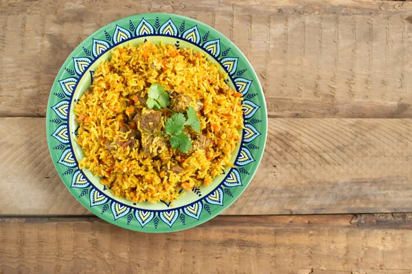 Doğu mutfağı tabağı, tavada kuzu pilavı, ahşap arka planda..