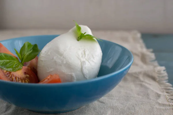 Grande mozzarella con fette di pomodoro e basilico in una pla blu — Foto Stock