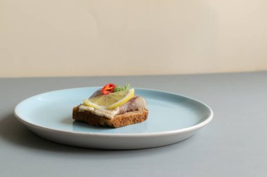 Limonlu salamura ringa balığı, acı biber ve dereotlu sandviç. Sağlıklı yiyecekler. Minimalizm. Gri arkaplan.