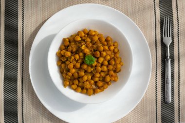 Kavrulmuş nohut, soğan ve beyaz bir tabakta hafif arkaplanda köri. Vejetaryen yemeği. Sağlıklı beslenme