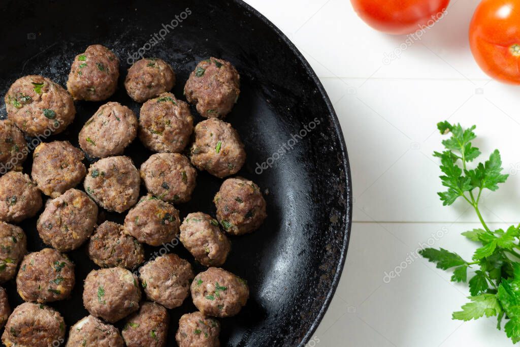 Homemade fried meatballs with herbs in a pan on a white background. Swedish traditional cuisine.