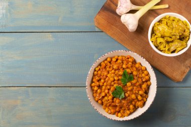 Kremalı bir tabakta Chana Masala ve mavi ahşap arka planda köri ve sarımsaklı tavuk. Geleneksel Hint mutfağı. Üst Manzara. Boşluğu kopyala.