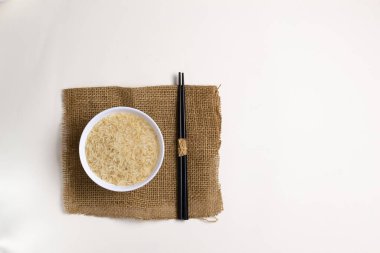 Çubuklu çuval bezi olan beyaz bir kasede pilav. Kırsal tarzda. Çin yemeği konsepti. Uzayı kopyala Üst görünüm