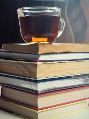 Kitaplar yığılmış ve bir bardak çay