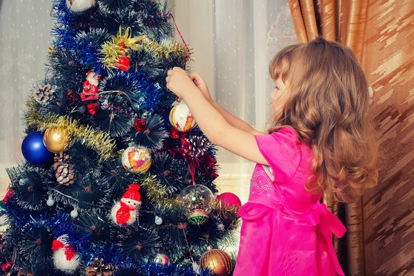 Çocuk Noel ağacını süslüyor.