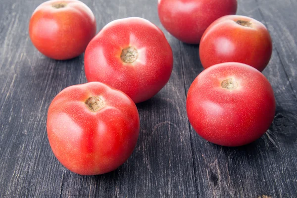 Pochi pomodori maturi sdraiati su una superficie di legno — Foto Stock