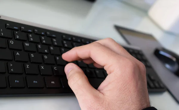 Hand die typt op het zwarte toetsenbord — Stockfoto
