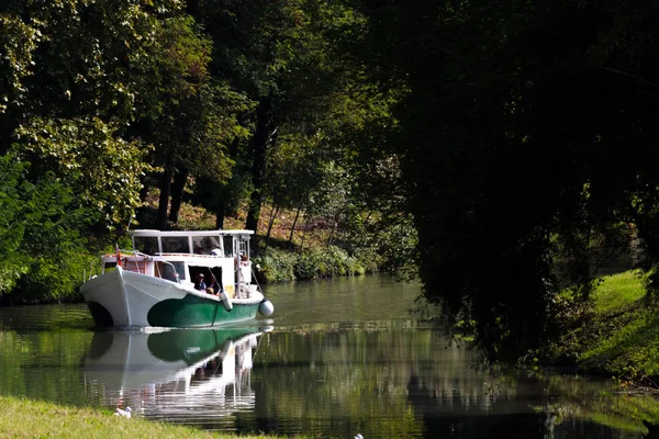 Човен, який повільно перетинає річку серед рослинності — стокове фото
