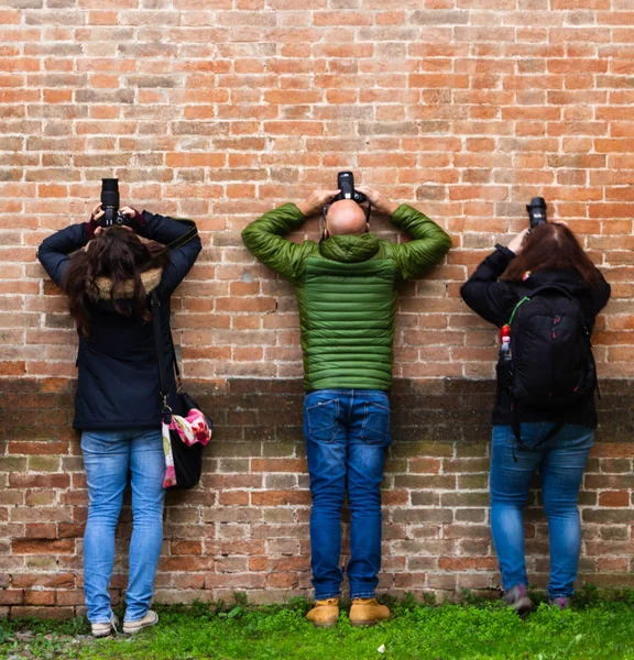 Drei nach oben schießende Fotografen lehnen sich an die Wand — Stockfoto