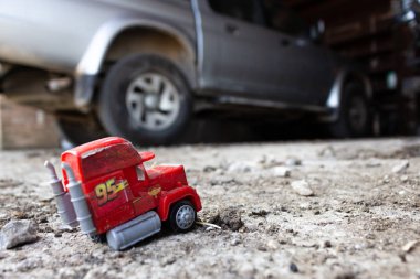 Kirli ve eski bir kamyonetin arka planındaki kaldırımda terk edilmiş bir kamyonun modeli.