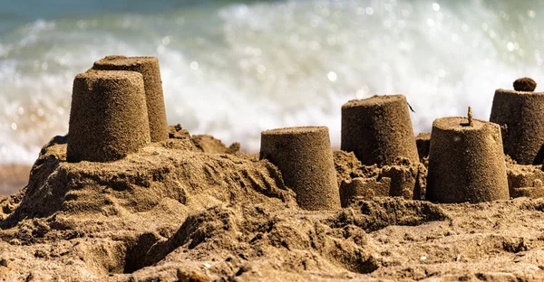 Sandburg im Vordergrund vor dem Hintergrund einer Meereswelle lizenzfreie Stockbilder