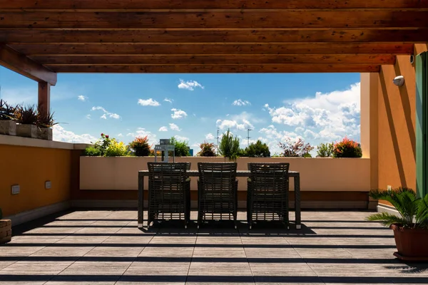 Обеденный стол из ротанга и стулья на террасе под голубым небом — стоковое фото