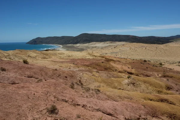 The moon-like colored clay hills of the New Zealands Cape Reinga in Northland, and Te Werahi Beach