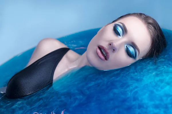 Menina modelo de moda bonita tomando banho azul, spa e conceito de cuidados com a pele. Rosto e mãos saudáveis . — Fotografia de Stock