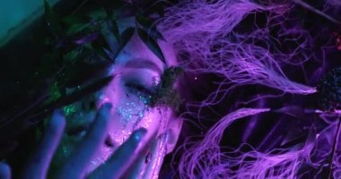 Güzel bir hayalet kız gölde sisli bir şekilde uzanıp kameraya bakıyor. 4k görüntü kalitesi