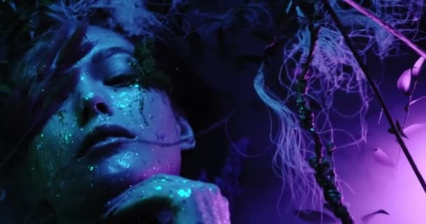 Millennial enigmatica bella ragazza con insolita acconciatura tinta vicino parete al neon incandescente di notte. Capelli blu, paillettes dorate come lentiggini, piercing al naso. Misterioso hipster adolescente in occhiali . — Video Stock