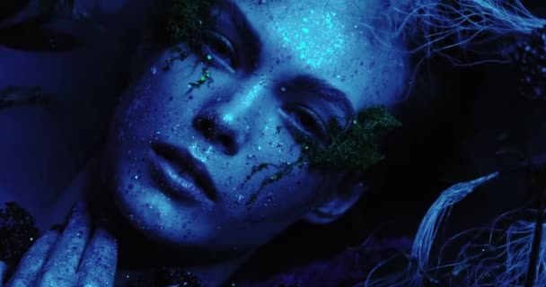 Фантастичний світ навколо чарівного диму в неоні світяться різні кольори синій, бірюзовий, фіолетовий, фея ельфійська дівчина лежить в тумані. 4k роздільна здатність крупним планом вид зверху — стокове відео