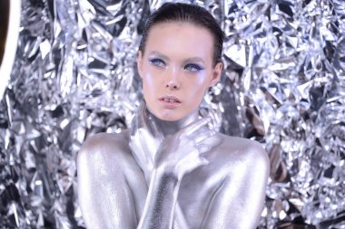 Güzel, genç, esmer, uzun saçlı, yaratıcı bir kadın. Pullarla makyaj yapıyor.