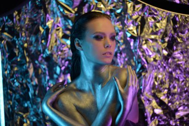 Model metalik gümüş dudaklar ve neon mavisi ve mor renkli yüzlü kadın, stüdyoda poz veriyor, güzel kız, parıldayan makyaj, renkli..