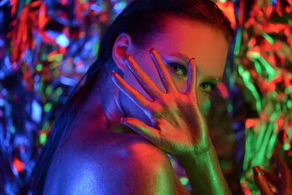 High Fashion model woman in colorful bright lights posing in studio, night club. Portrait of beautiful sexy girl with trendy make-up. Neon Art design, colorful make up. On colourful vivid background