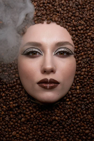 beautiful woman face with closed eyes in the coffee beans