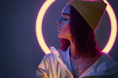 Gece kulübünde poz veren renkli parlak neon ışıklı yüksek model esmer kadın. Güzel seksi kız, son moda parlak makyaj, metalik gümüş dudaklar. arkaplan Violet rengi