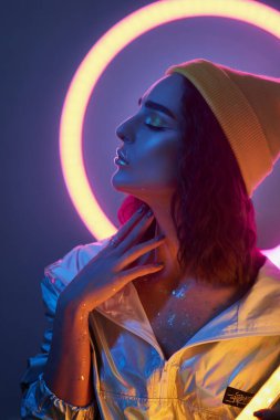 Hipster igen teen beautiful model şık gözlüklü kulaklıklar takın Mor stüdyo arka planında yeni havalı müzik standı 80 'lerin kulüp mavi parti ışığı, profil görünümü