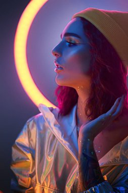 Renkli parlak neon ışıklarıyla stüdyoda poz veren yüksek model. Parlak makyajlı güzel bir kızın portresi. Sanat tasarımı canlı biçimi.
