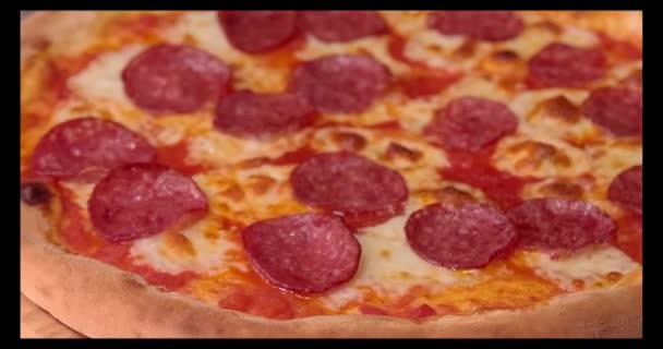 用小刀把披萨切在木制桌子上,把它切好.皮萨里略在意大利披萨店用滚刀切热披萨。意大利食品的加工过程。食品和小吃概念 — 图库视频影像