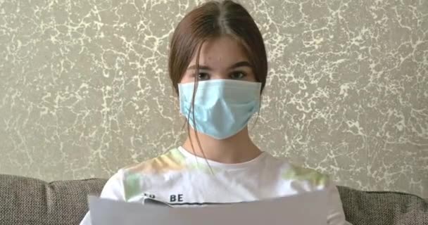 Ung flicka stanna hemma koncept. kvinna i medicinsk mask innehav skylt som säger stanna hemma covid-19. Video 4k upplösning — Stockvideo