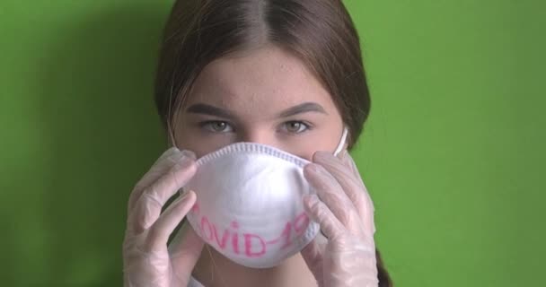 Молода жінка знімає медичну маску COVID-19. Дівчина глибоко дихає, дивлячись на камеру. Ізольовані на зеленому фоні хромокі. Охорона здоров'я та медична концепція. Портрет крупним планом. Роздільна здатність 4k — стокове відео