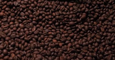 Ağzında kaşıkla kahve çekirdeklerine daldırılmış yüksek model bir kadının portresi. Güzel genç kız makyajı. Kameraya bakıyorum. Kahve yaşam tarzı. Yüksek kalite 4k video