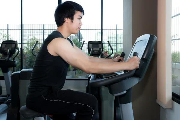 Um homem no ginásio. Asiático jovem homem exercitando suas pernas fazendo cardio — Fotografia de Stock