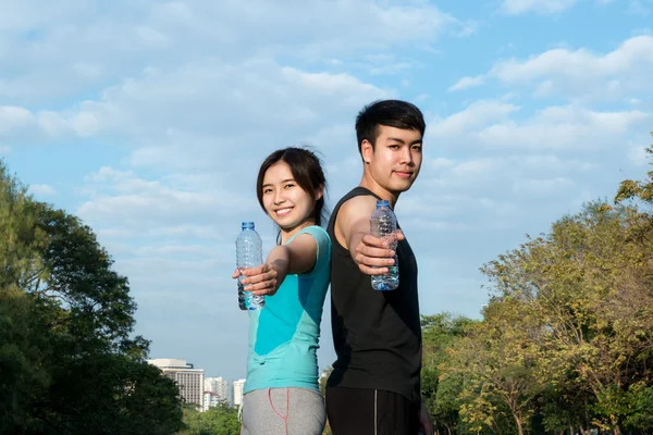 Азиатский молодой человек и женщина пьют воду из бутылки воды после — стоковое фото