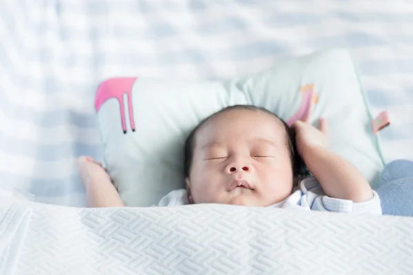 Asian newborn boy sleeping over his white bed covered with a bla — Stock Photo, Image