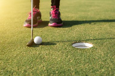Yeşil koyarak bir deliğe golf topu koyarak Golf oyuncu. 