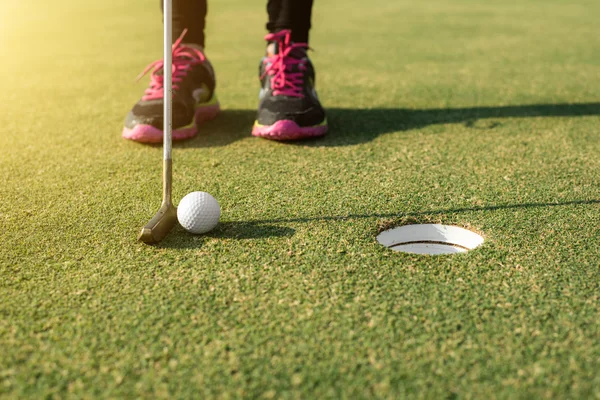 Golfspelare på putting green sätta golfboll i ett hål. — Stockfoto
