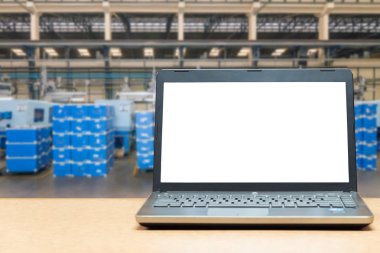 Laptop with blank screen on table with blur warehouse cargo in f clipart