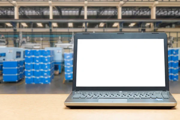 Laptop with blank screen on table with blur warehouse cargo in f