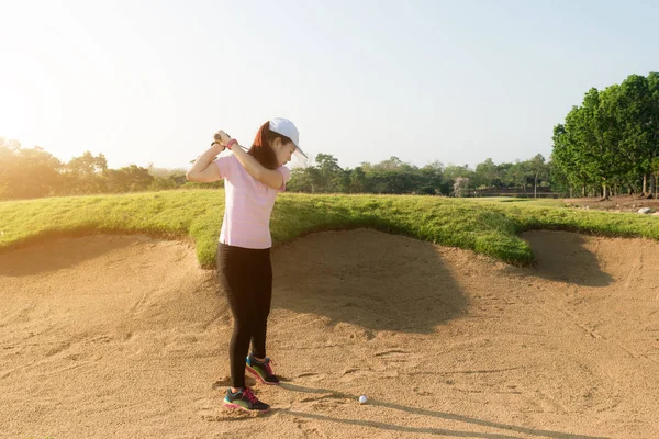 Asian woman golf player hitting golf ball out of sand trap. Golf