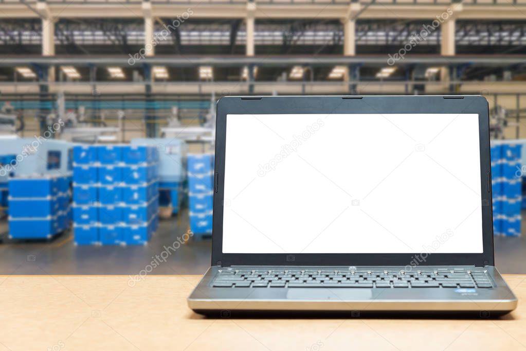 Laptop with blank screen on table with blur warehouse cargo in f