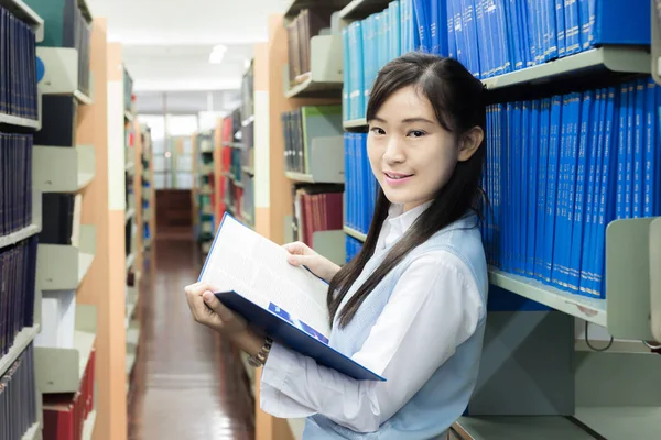 Asian student in uniform reading in the library at university. — Stock Photo, Image